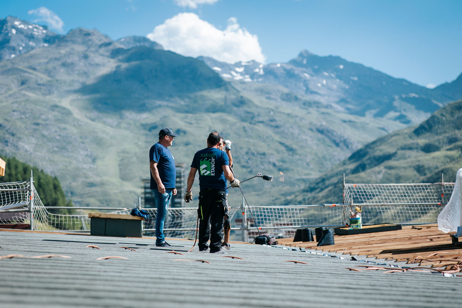 Des hommes sur un toit réalisent des travaux d'étanchéité sur le bâtiment