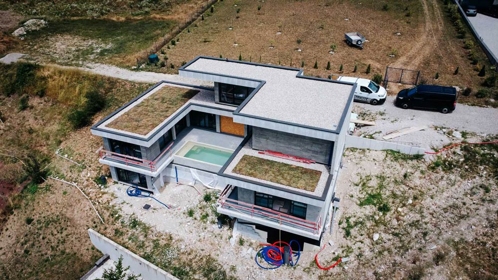 Un bâtiment en construction est recouvert de toitures végétalisées et de toit-terrasses